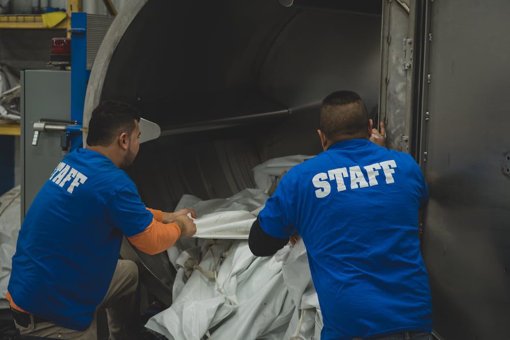 two workers packing a tent into a truck